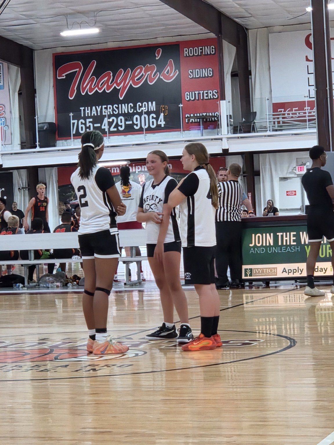 Three Team Infinity girls players communicate together on the court.